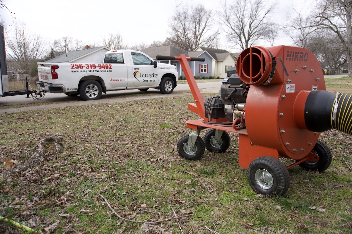 Integrity Services truck and large orange equipment on grassy area.