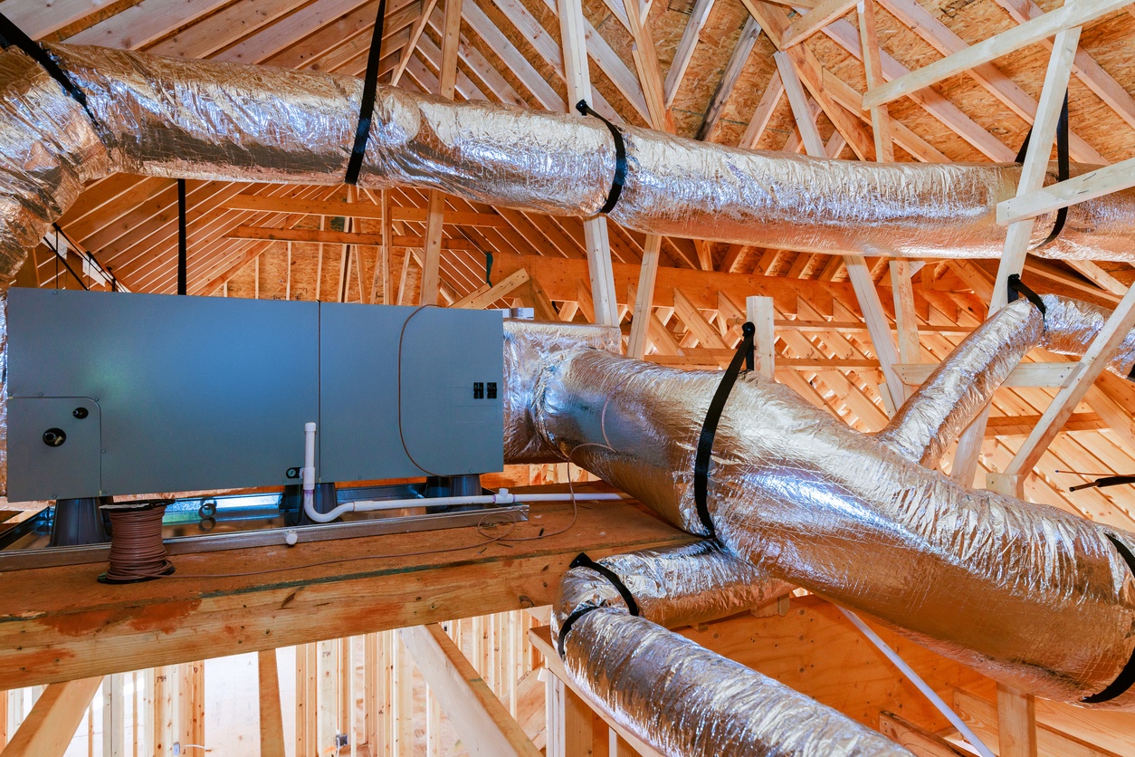 Attic HVAC system with insulated ventilation ducts in a wooden roof structure.